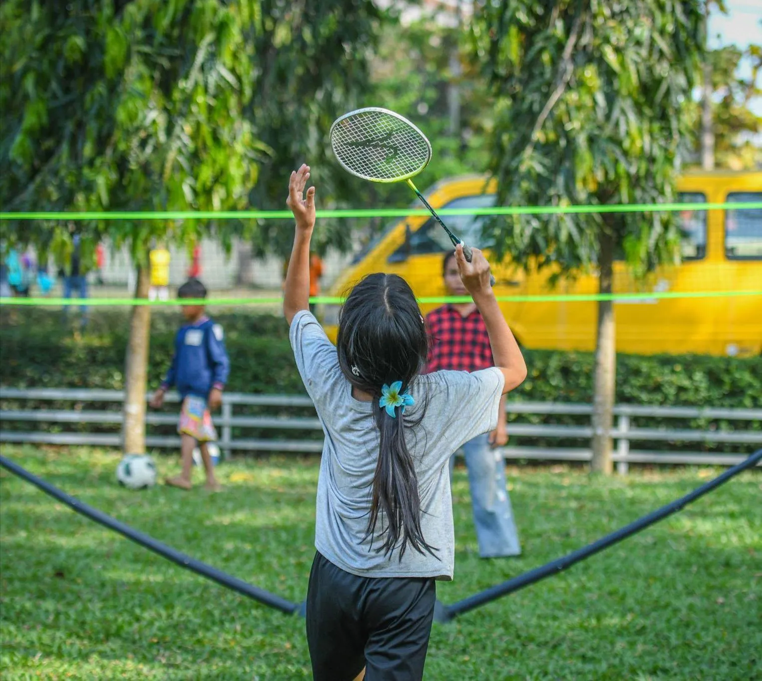 Une jeune fille frappe un volant de badminton en plein air