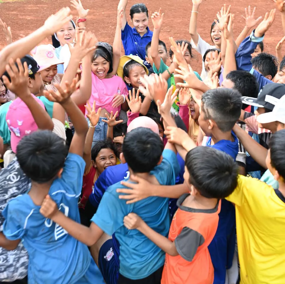 Des enfants lèvent les bras en riant lors d'un camp de rugby dans un village vietnamien