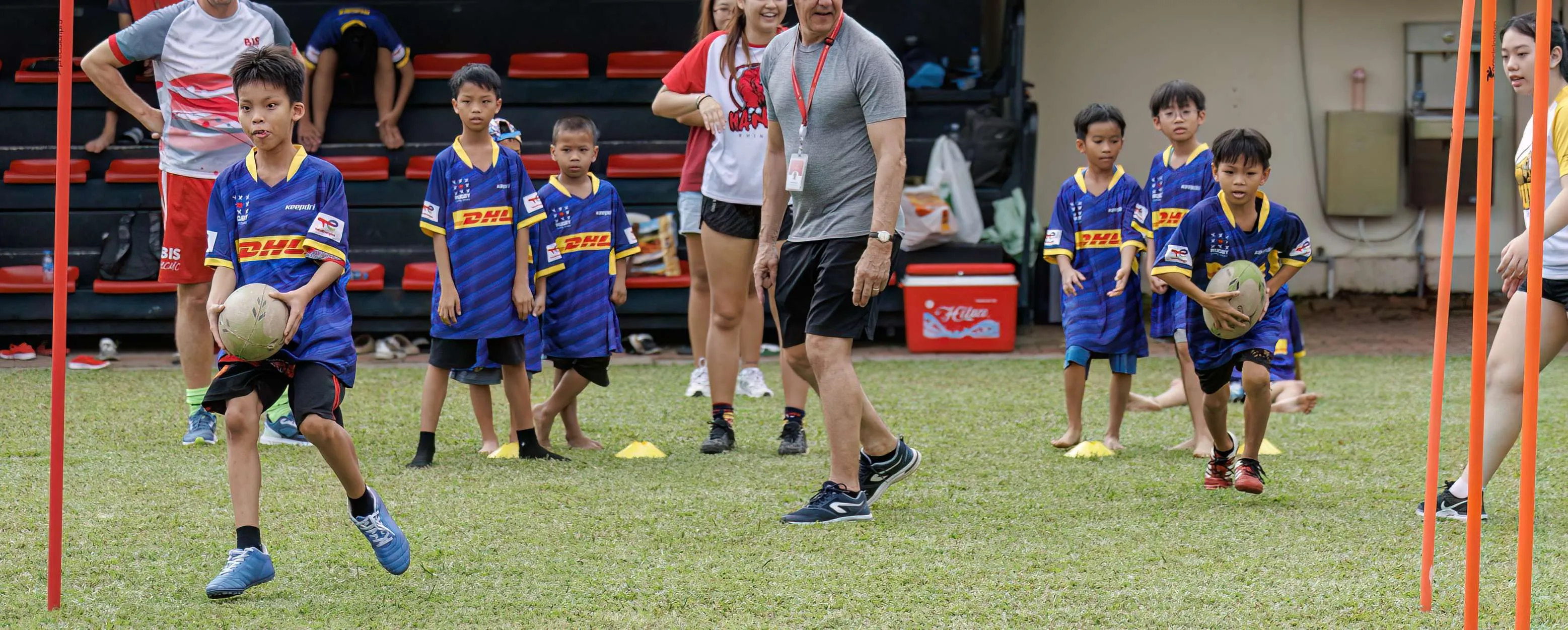 Des enfants en maillot Rugby Cùng Nhau courent ballon en main lors d'un entraînement