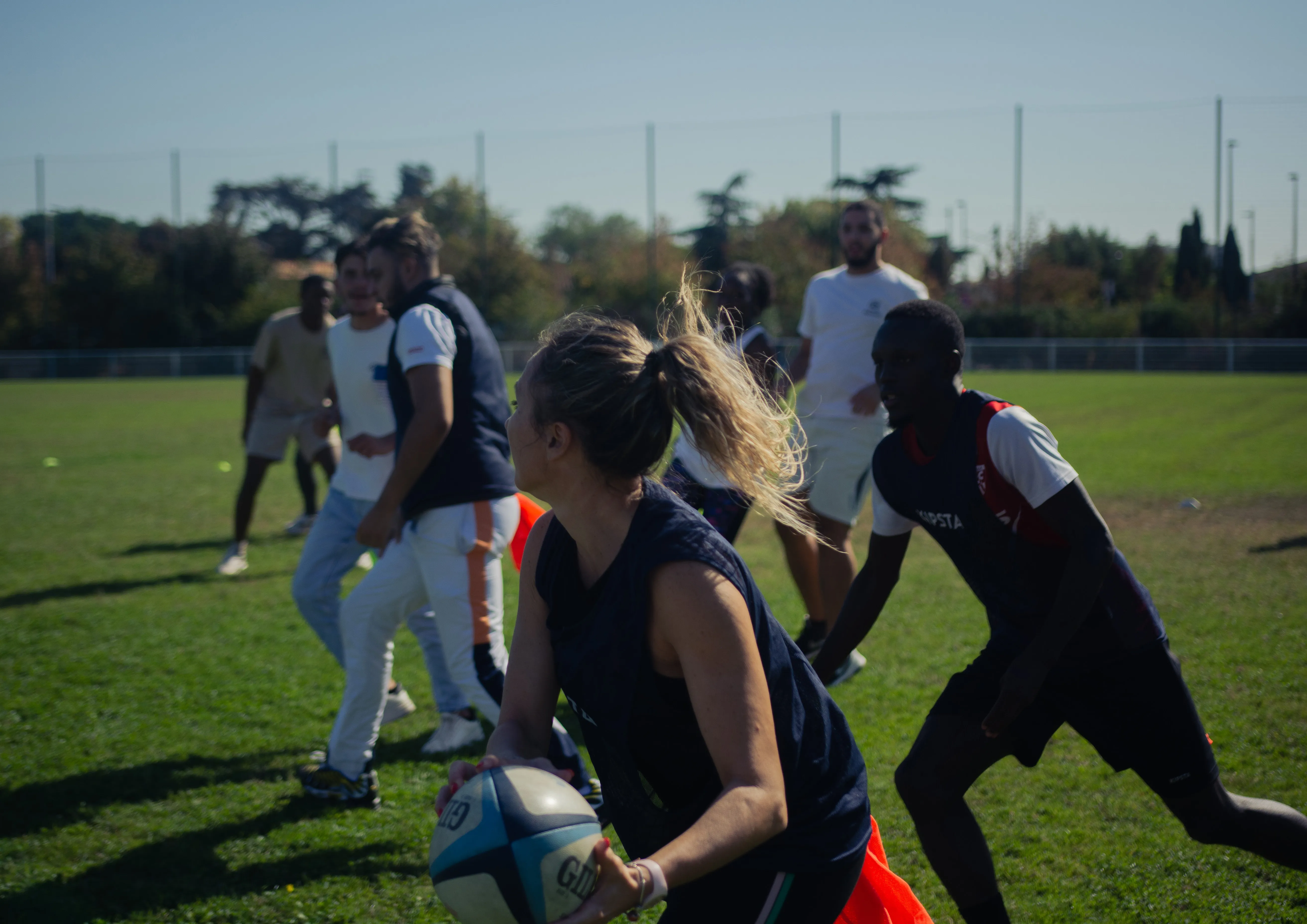 Une jeune joueuse s'apprête à passer le ballon lors d'un match de rugby Rebonds! en plein air